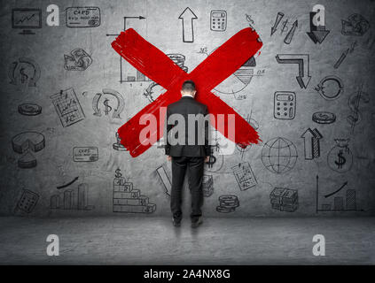 Businessman lean his forehead to concrete wall with business doodles and big red cross in the middle Stock Photo