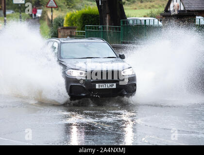 A car makes it's way through the flooded ford in Castle Street Kenilworth after recent heavy rain and storms Stock Photo