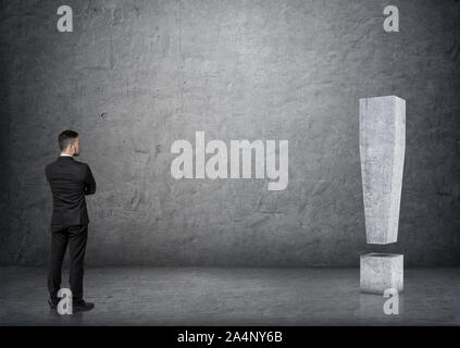 Back view of businessman touching big 3D concrete exclamation mark Stock Photo