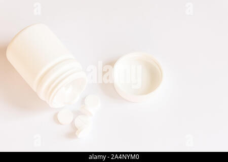 White pills in a bottle on white background. Mockup for design. Copy space. Stock Photo