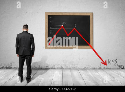 Businessman standing in front of blackboard with falling diagram Stock Photo