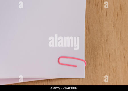 Blank paper clipped on wooden desk background. Office workplace. Mockup for design. Stock Photo