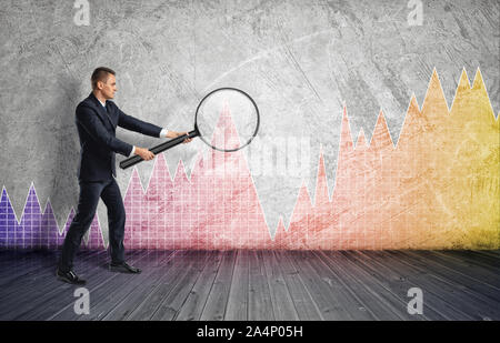 Businessman looking through a magnifier on colorful diagram Stock Photo