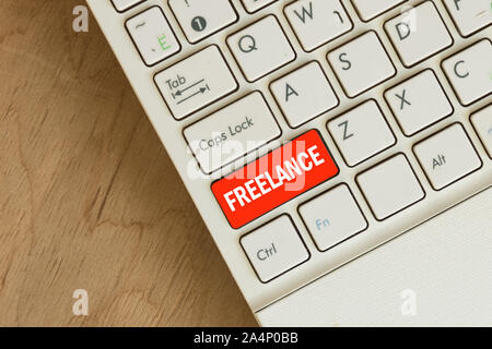 Laptop keyboard top view on wooden table background. Freelance text . Copy space. Stock Photo