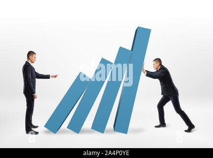 Rival businessman pushing the blocks of graph that another holding back from falling Stock Photo