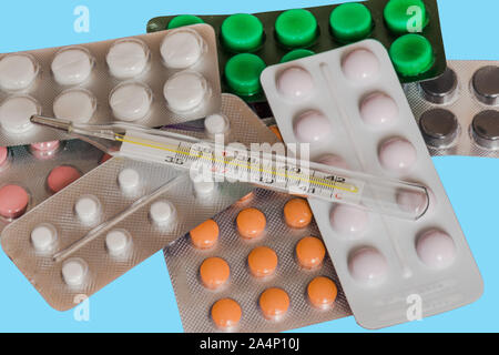 Different medicine pills and thermometer on pastel color background. Health care concept. Composition with medicaments. Stock Photo