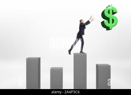 Businessman standing on grey column with his hands up to the big dollar sign Stock Photo