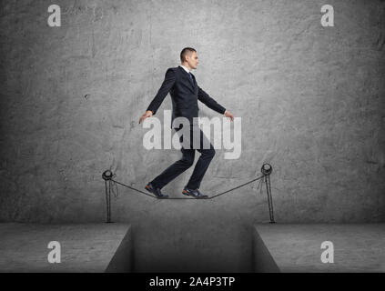 Businessman walking on drawn tightrope over the gap Stock Photo