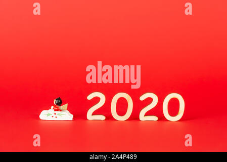 Christmas composition with wooden figures 2020 on a red background. Minimalization, space for text Stock Photo