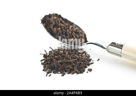 Dried black tea leaves in spoon isolated on white background. Stock Photo