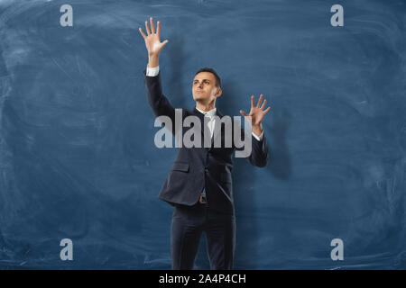 Businessman is putting imaginary buttond on the blue blackboard background Stock Photo