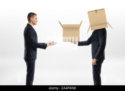 Businessman with cardboard box on his head passed another one to man Stock Photo