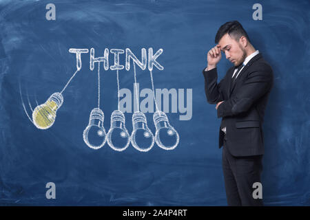 Businessman standing with hand on his forehead near word 'think' Stock Photo