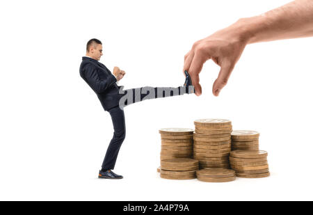 Businessman is hitting with leg huge hand trying to grab his profit Stock Photo