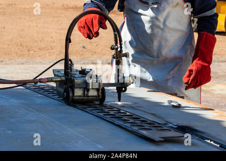 Motswana welder worker in a Botswana workshop, using an acetylene torch to cut in straight line, roller torch, Stock Photo