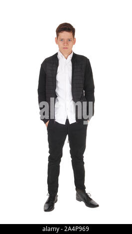 A serious looking teen boy standing with his hands in his pocket, in a  black jacket and pants, isolated for white background Stock Photo