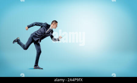 A businessman in a runner position ready to start on blue background. New business. Stock Photo