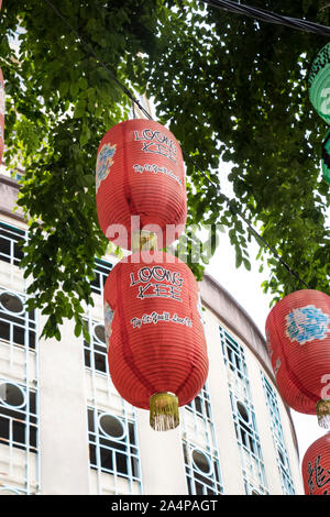traditional red and green paper lanterns hanging from trees in a kuala lumpur street malaysia Stock Photo