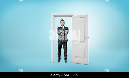 A bearded businessman stands with arms crossed inside a white cut out doorframe. Stock Photo
