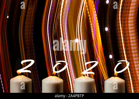 Happy New Year 2020 is written with candle flames on party striped colors background. Concept of greeting card, holiday celebration. Top view, flat la Stock Photo