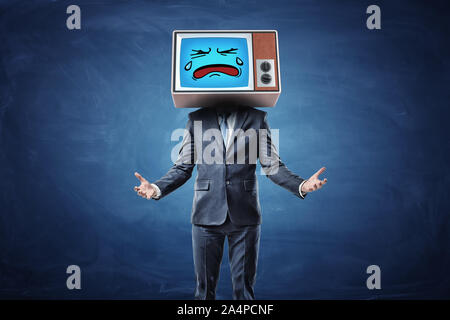 A businessman with hands turned in front of him with palms up and wearing a TV with a sad crying face on his head. Stock Photo