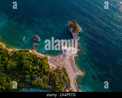 Aerial view of Sveti Nikola, Budva island, Montenegro. Hawaii beach, umbrellas and bathers and crystal clear waters. Jagged coasts Stock Photo