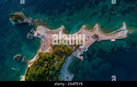 Aerial view of Sveti Nikola, Budva island, Montenegro. Hawaii beach, umbrellas and bathers and crystal clear waters. Jagged coasts Stock Photo