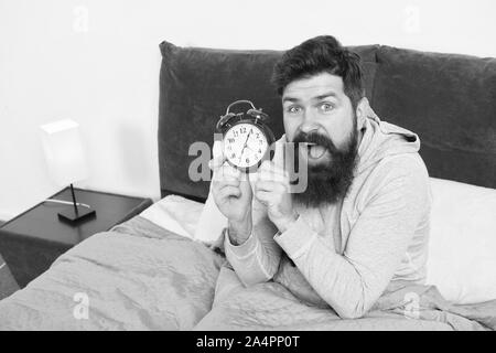 Man bearded hipster sleepy face waking up. Daily schedule for healthy lifestyle. Again unhappy in morning. Alarm clock ringing. Problem early morning awakening. Get up early. Tips for waking up early. Stock Photo