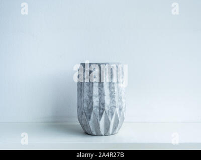 Concrete pot. Empty modern geometric concrete planter on wooden shelf isolated on white background. Stock Photo