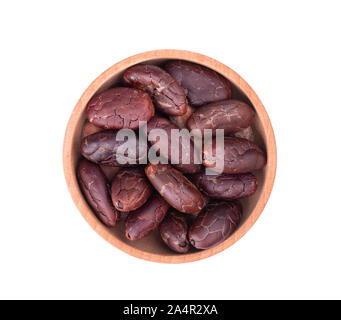 Peeled cocoa beans in the wooden bowl, isolated on white background. Roasted and aromatic cocoa beans, natural chocolate. Top view. Macro. Stock Photo