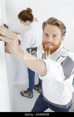 young builder applying of the plaster on the wall Stock Photo