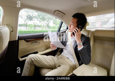 Asian man talking on mobile phone and looking out of window Stock Photo