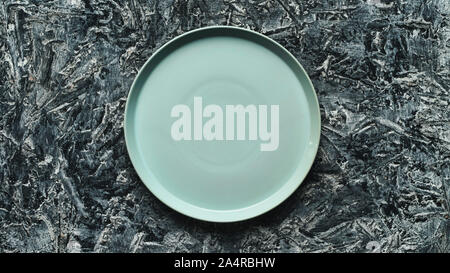 Blue empty plate on frozen and snow-covered black background. Christmas concept Stock Photo