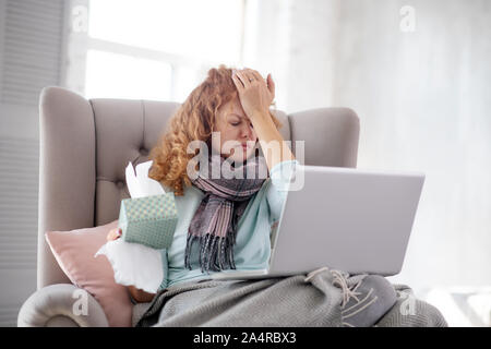 Curly woman holding pack of napkins while having stuffy nose Stock Photo