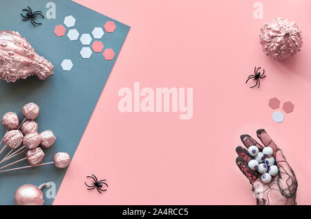 Creative paper craft Halloween flat lay with copy-space. Pink and grey split paper background with black spiders and paper hexagons. Hand in black mes Stock Photo