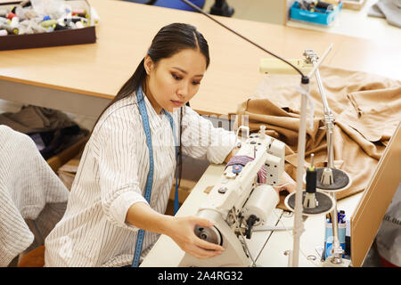 Asian young seamstress working with sewing machine she sewing clothes in workshop Stock Photo