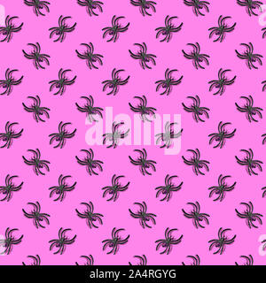 Halloween decorations concept - seamless pattern with black plastic spiders on glowing pink background Stock Photo