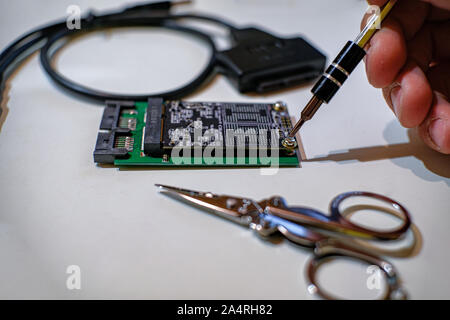 Human hands working on ssd chipset computer components with screwdriver Stock Photo
