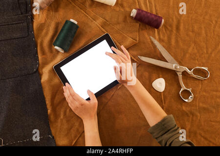 Close-up of fashion designer using tablet pc while working with different types of fabric in workshop Stock Photo