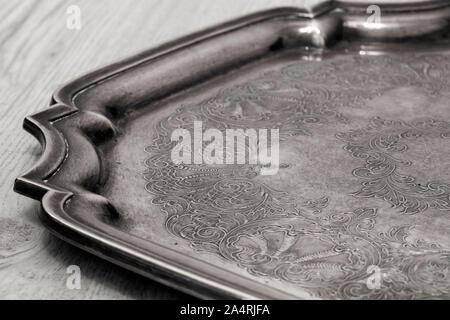 Antique tarnished silver tray with engraved pattern on a grey wood background Stock Photo