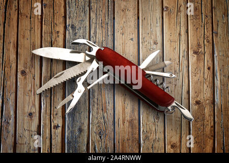 Well used and aged swiss multifunction knife on textured wooden table Stock Photo
