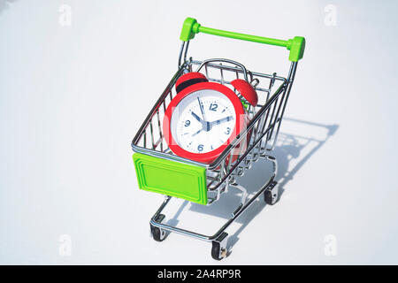 Red clock on the shopping cart, lack of time, waste of time, purchasing time, Shopping concept, Business concept. Stock Photo
