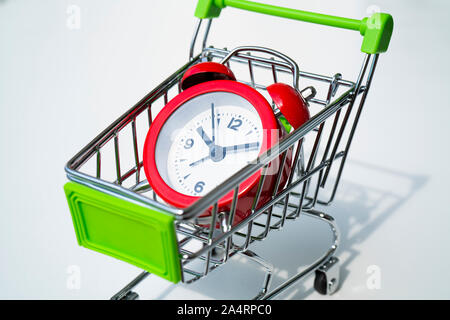 Red clock on the shopping cart, lack of time, waste of time, purchasing time, Shopping concept, Business concept. Stock Photo
