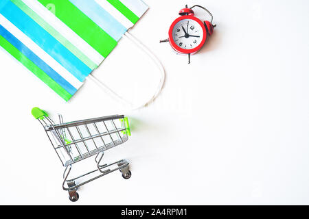 Red clock, shopping cart and paper bag on isolated white backgroun. Lack of time, waste of time, purchasing time, Shopping concept, Business concept. Stock Photo