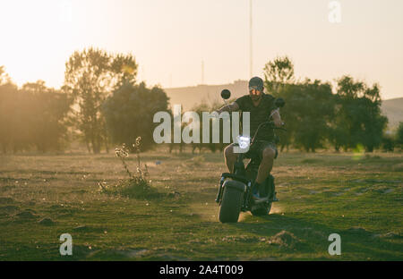 man on a motorized bicycle in sunset time Stock Photo