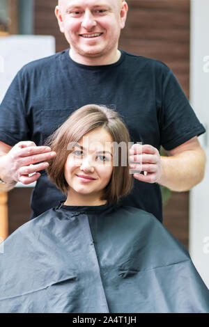 Hair stylist and client are looking at mirror before hair styling. Haircut, hair care, beautician concept. Stock Photo