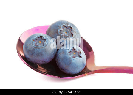 Three blueberries in purple metal spoon on white background Stock Photo