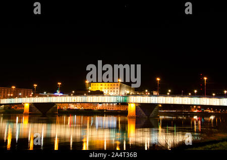 Beautiful mesmerizing night scene panoramic view of Linz Nibelungen bridge over Danube river with golden lights colorful reflexions on water surface. Stock Photo