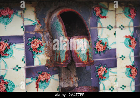 Rusting metal flue surrounded by colourful tiles in kitchen of abandoned croft, Isle of Lewis and Harris, Outer Hebrides, Scotland Stock Photo