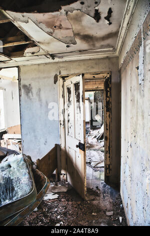 Interior of abandoned croft with mattress, damp, collapsing ceiling and view through internal door, Isle of Lewis and Harris, Outer Hebrides, Scotland Stock Photo